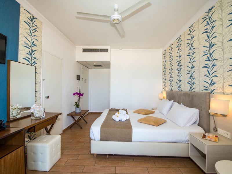 Chambre d'hôtel moderne avec lit double, deux oreillers, lampes et TV.