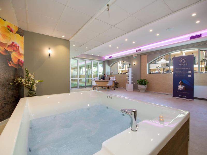 Espace bien-être moderne avec jacuzzi, sièges et éclairage d'ambiance.