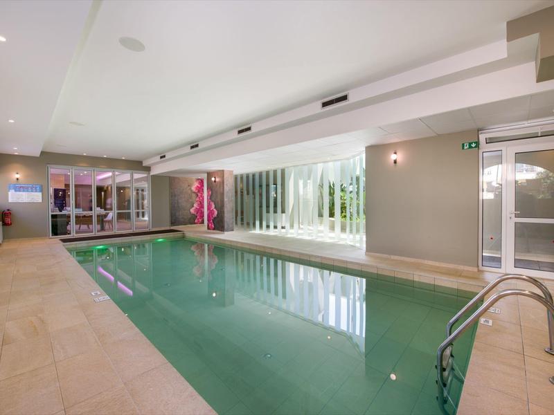 Piscine intérieure moderne avec grandes fenêtres et chaises longues confortables dans un hôtel