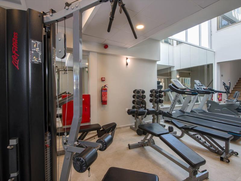 Salle de sport bien éclairée avec des appareils modernes et des poids dans un espace hôtelier.