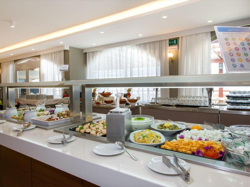 Buffet avec salades et plats dans un restaurant d'hôtel lumineux avec séparation en verre.