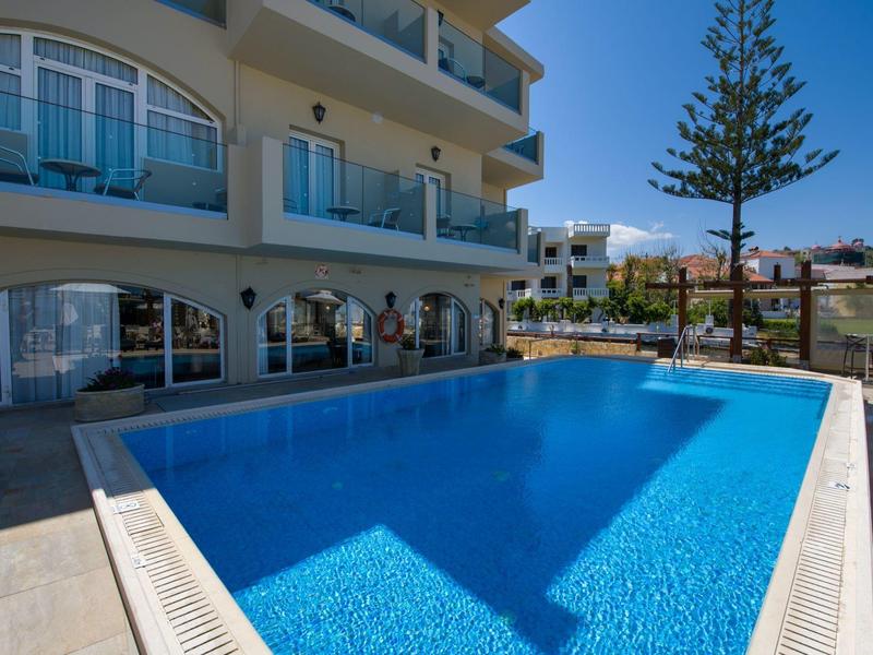 Piscine bleue claire à côté d'un hôtel moderne sous un ciel ensoleillé.