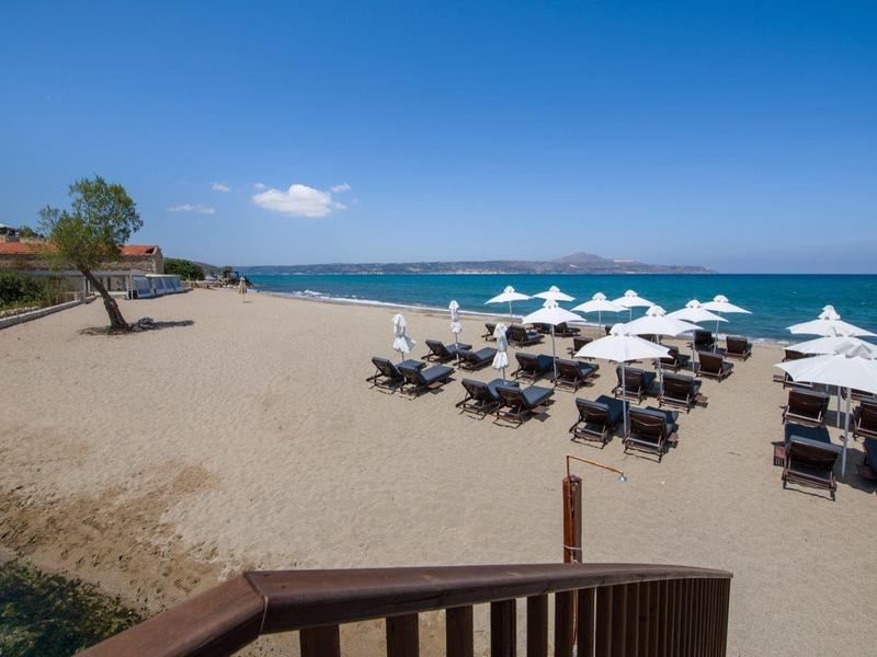 Plage ensoleillée avec parasols, chaises longues et mer bleue calme sous un ciel clair.
