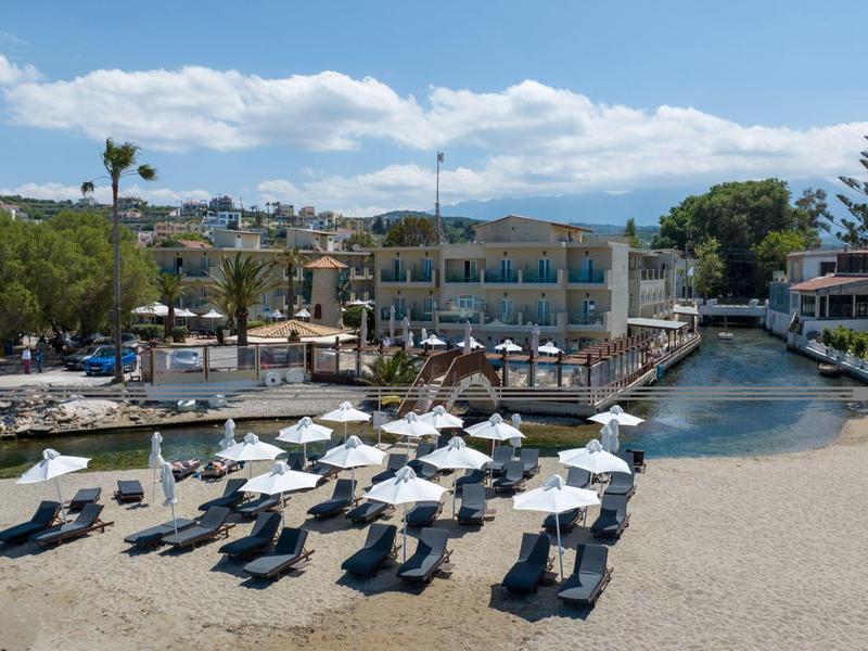 Chaises de plage avec parasols sur plage sablonneuse près de la marina et hôtels sous ciel bleu