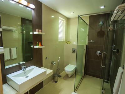 Modernes Badezimmer mit Glasdusche, Wand-WC, Waschbecken, Spiegel und weißen Handtüchern.