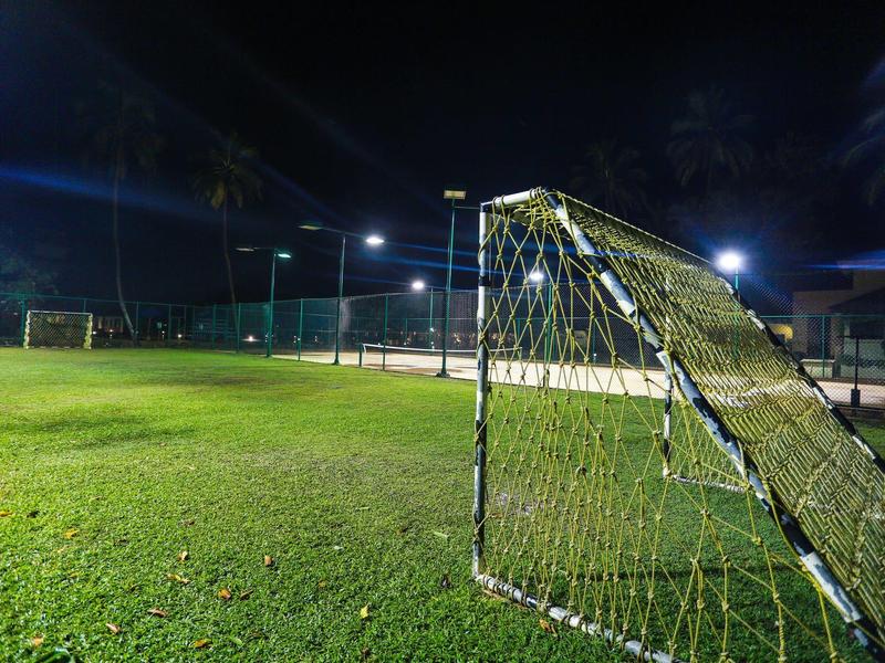 Lit soccer field with goal at night on well-maintained grass.