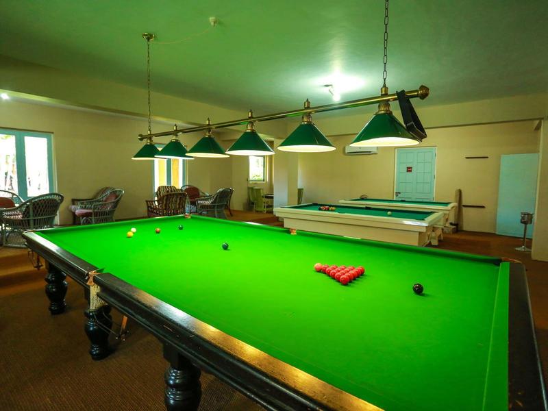 Billiard tables in a cozy, warmly lit room with green lampshades and seating areas.