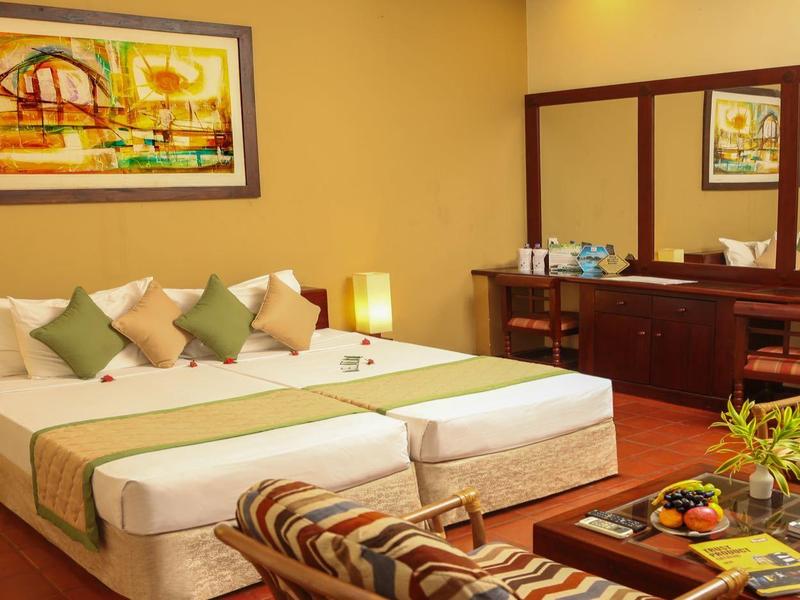 Cozy hotel room with large bed, seating area, and wooden paneling.