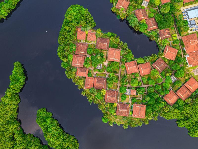 Aerial view of red-roofed bungalows surrounded by water and lush greenery.