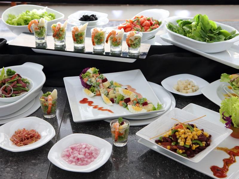 Various salads and small appetizers artfully arranged on white plates.