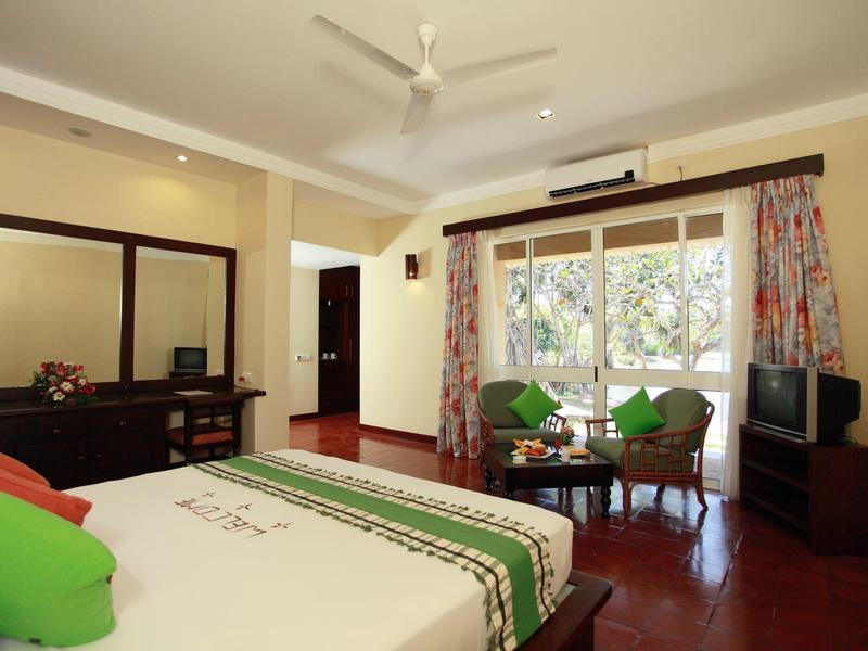 Bright hotel room with double bed, seating area, and large window overlooking greenery.
