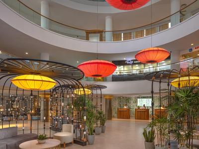 Hell eingerichteter Innenraum mit runden Lampen, grünen Pflanzen und moderner Sitzmöblierung.