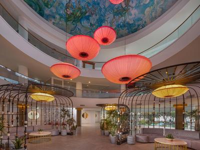 Modernes Hotelinterieur mit großen roten und gelben Lampen und kunstvoll bemalter Kuppeldecke.