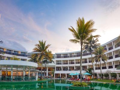 Moderne Hotelanlage mit Pool und Palmen bei Sonnenuntergang.