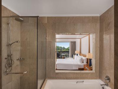 Modernes Badezimmer mit Dusche und Badewanne, beige Fliesen, Blick ins helle Schlafzimmer.