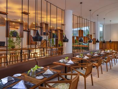 Modern eingerichtetes Restaurant mit Holztischen, Lederbänken und hängenden Lampen.