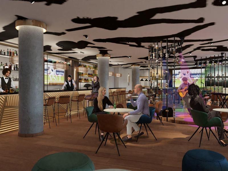 Modernes Café mit Holzfußboden, runden Tischen, bunten Stühlen und großer Bar im Hintergrund.