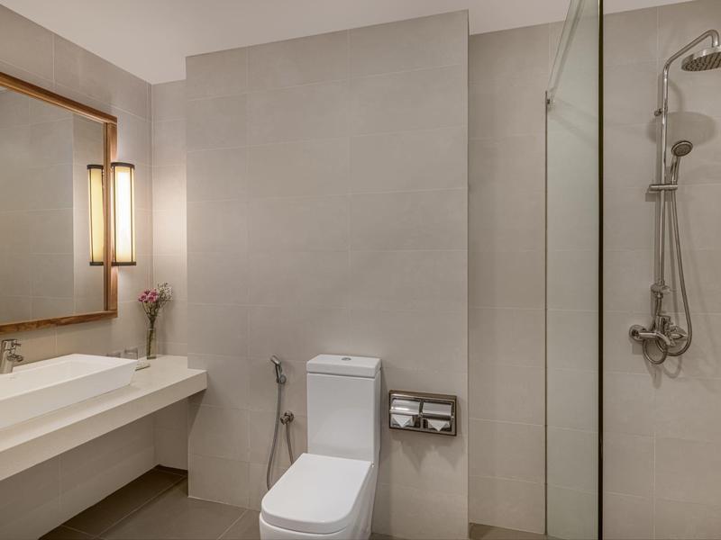 Modernes Badezimmer mit großem Spiegel, Waschtisch, WC und begehbarer Dusche mit Glaswand.