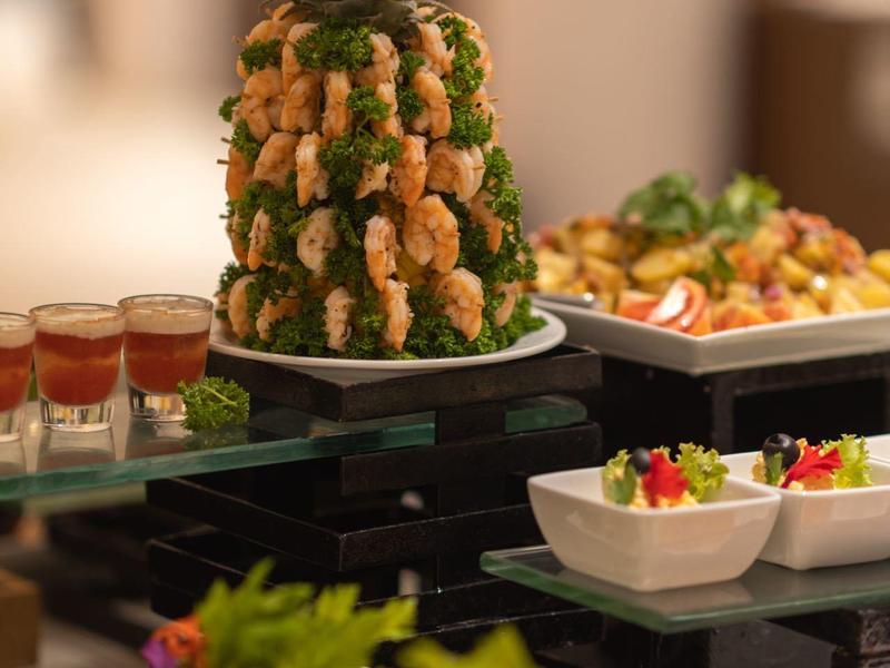 Buffet mit Ananas, frischen Garnelen, Salaten und kleinen Gläsern mit roter Sauce.