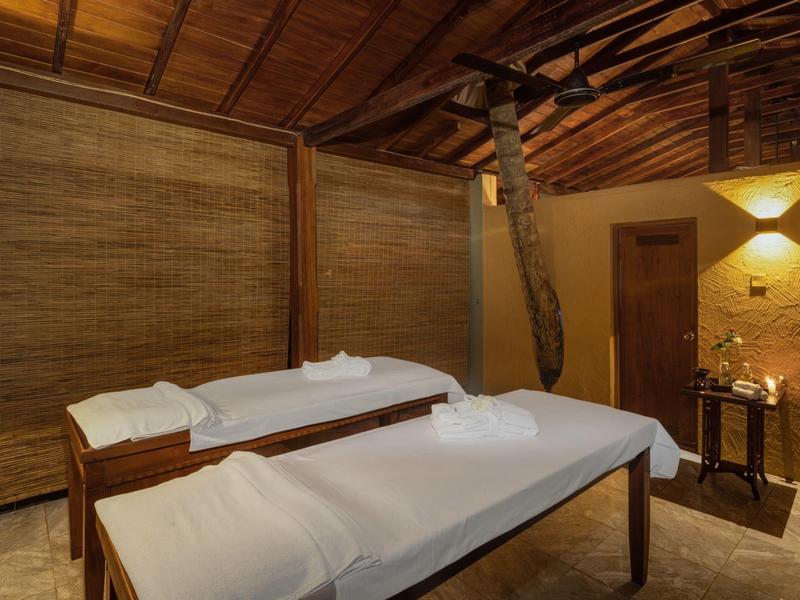 Gemütlicher Wellnessraum mit zwei Massageliegen, Holzwänden, Decke und warmem Licht.