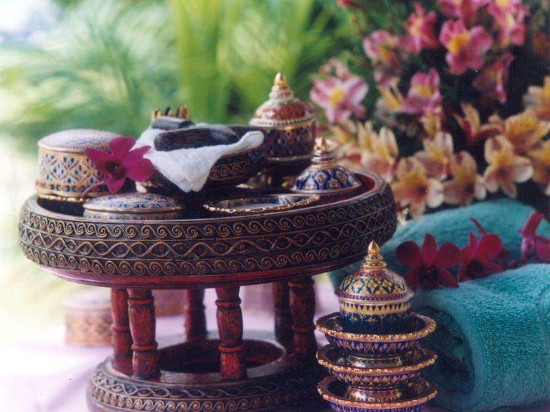 Traditioneller, verzierter Holztisch mit kleinen goldverzierten Behältern und farbenfrohem Hintergrund.