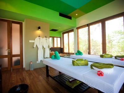 Modernes Spa-Zimmer mit zwei Massageliegen, grünen Handtüchern und floralen Akzenten.