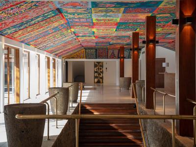 Innenraum eines Hotels mit buntem, gemustertem Deckenmosaik und moderner, heller Einrichtung.