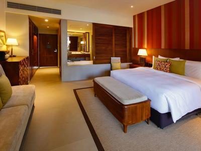 Modernes Hotelzimmer mit großem Bett, Sofa, Nachtlampen und warmen Holzakzenten.