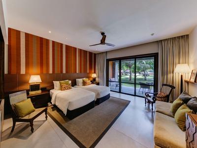 Modernes Hotelzimmer mit Doppelbett, Stühlen, Teppich und großem Fenster mit Blick auf Garten.