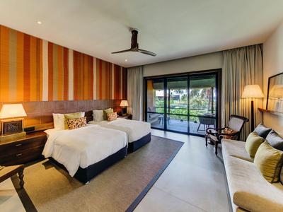 Modernes Hotelzimmer mit Doppelbetten, Holzvertäfelung und Blick auf Terrasse mit Garten.