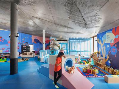 Bunter Indoor-Spielbereich mit Rutschen, Spielzeugen und Malereien in einem Hotel für Kinder.