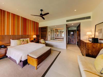 Elegantes Hotelzimmer mit großem Bett, Holzmöbeln und offenem Badezimmerbereich.