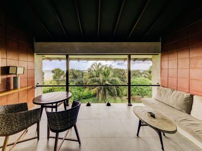 Moderner Hotelbalkon mit Sitzbereich und Blick auf grüne Palmenlandschaft.