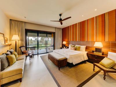 Geräumiges Hotelzimmer mit Doppelbett, Sessel, Schreibtisch und Balkon mit Blick ins Grüne.