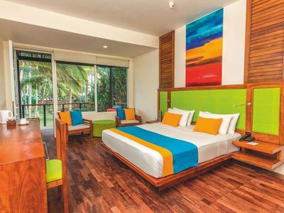 Nowoczesna sypialnia z dużym łóżkiem, kolorowymi poduszkami i drewnianą podłogą w pokoju hotelowym.