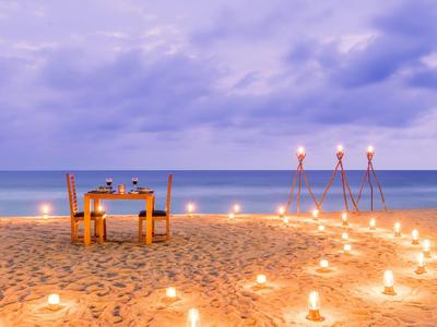 Romantisches Abendessen mit Kerzenlicht am Strand bei Sonnenuntergang.