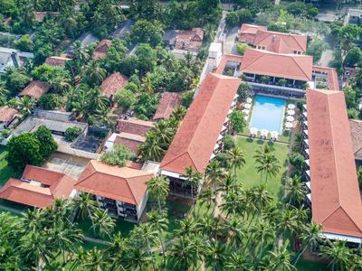 Zdjęcie z lotu ptaka ośrodka z czerwonymi dachami, basenami i bujną zielenią.