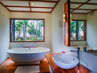 Nowoczesna wanna i umywalka z widokiem na tropikalny ogród przez duże okno.