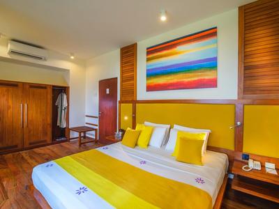 Jasny pokój hotelowy z dużym łóżkiem, kolorowym obrazem na ścianie i meblami drewnianymi.