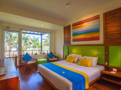 Nowoczesny pokój hotelowy z dużym łóżkiem, drewnianym wystrojem i widokiem na palmy przez duże okna.