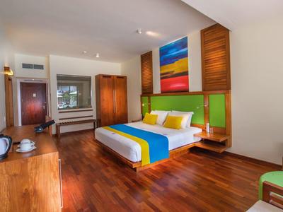 Nowoczesny pokój hotelowy z łóżkiem podwójnym, kolorową dekoracją ścian i drewnianymi meblami.