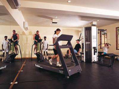 Mehrere Personen trainieren in einem modernen Fitnessraum mit Laufband und Trainingsgeräten.