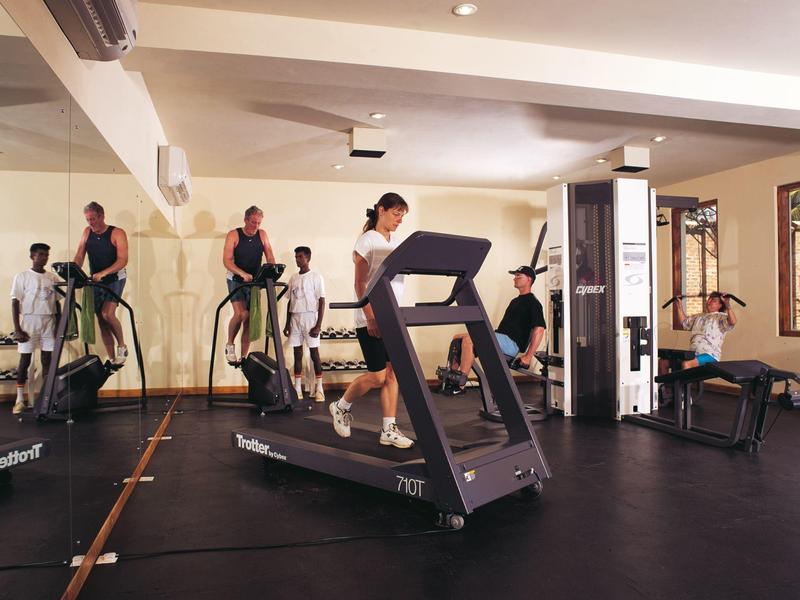 Ludzie ćwiczą w nowoczesnej siłowni z bieżniami i sprzętem fitness.