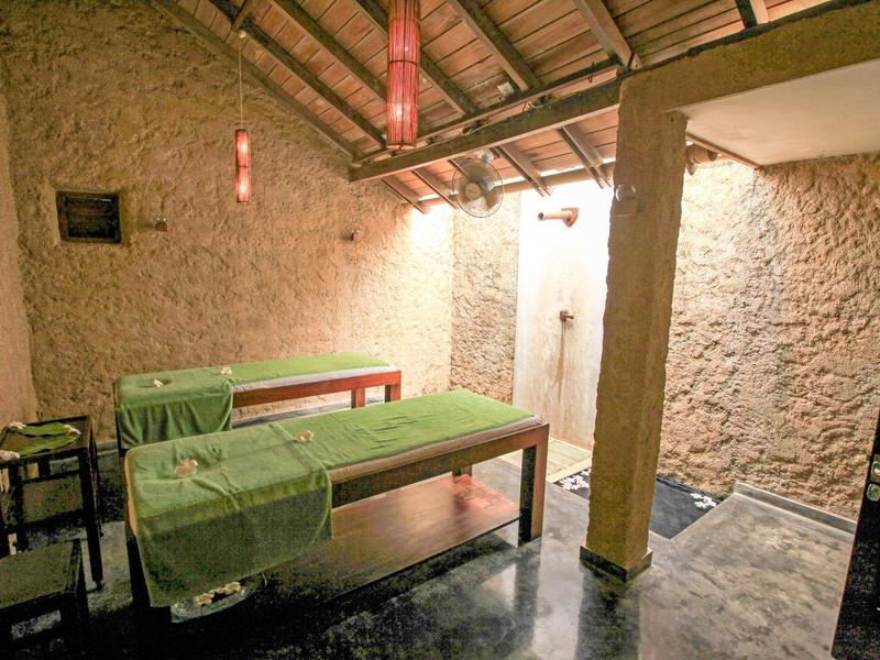 Prosto urządzone pomieszczenie do masażu z dwoma leżankami i otwartym drewnianym dachem.
