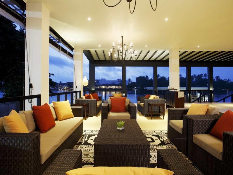 Salon d'hôtel confortable avec canapés, fauteuils et lustre réglable à la tombée de la nuit.