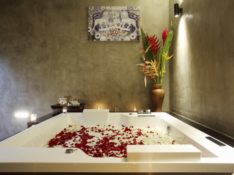 Baignoire luxueuse avec pétales de rose et bougies dans un cadre de spa élégant.