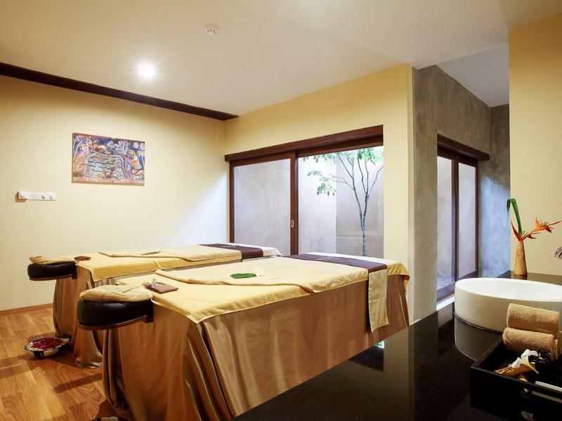 Salle de massage calme avec deux tables et éclairage chaud pour la détente.