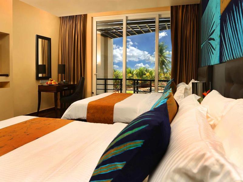Chambre d'hôtel moderne avec grands lits, terrasse et vue sur les montagnes et le ciel bleu.