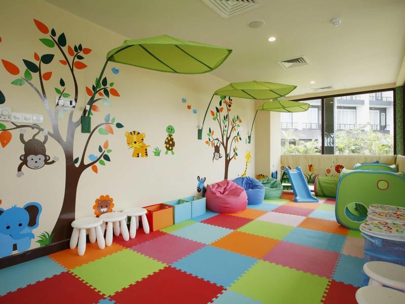 Salle de jeux colorée pour enfants avec poufs, éléments d'escalade et décorations murales animales.