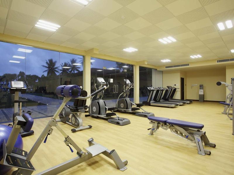 Salle de sport moderne avec divers équipements d'entraînement et grandes fenêtres avec vue.